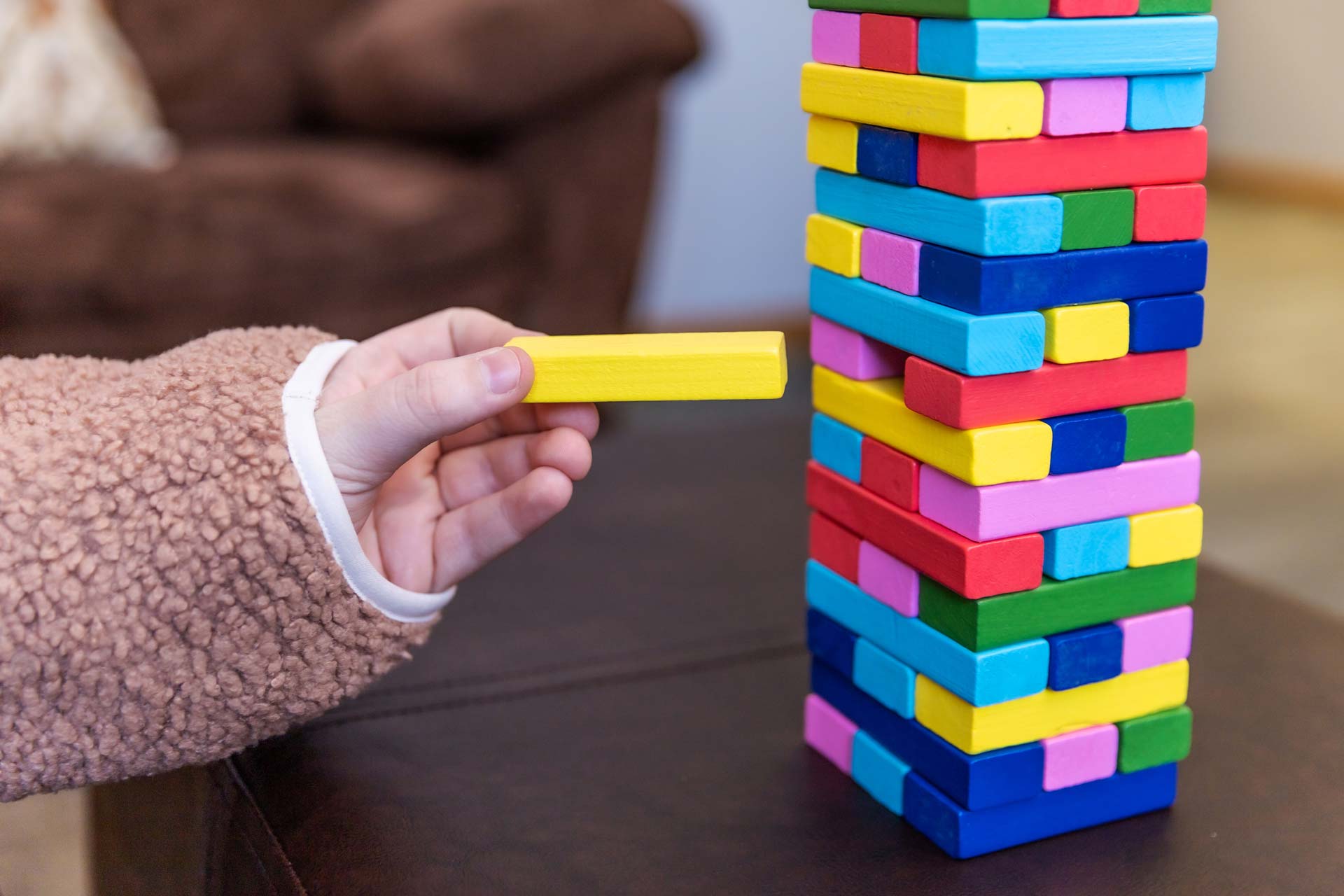 child stacking colored jenga blocks